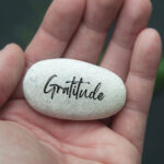 hand holding a stone with gratitude engraved on the stone