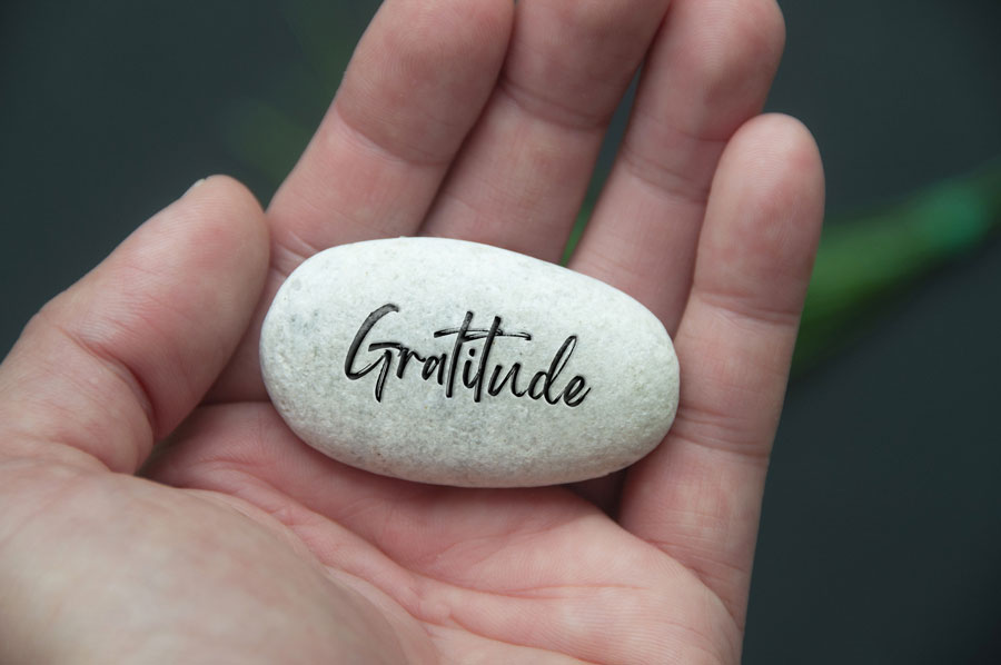 hand holding a stone with gratitude engraved on the stone