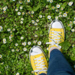 yellow sneakers in a daisy field - springtime