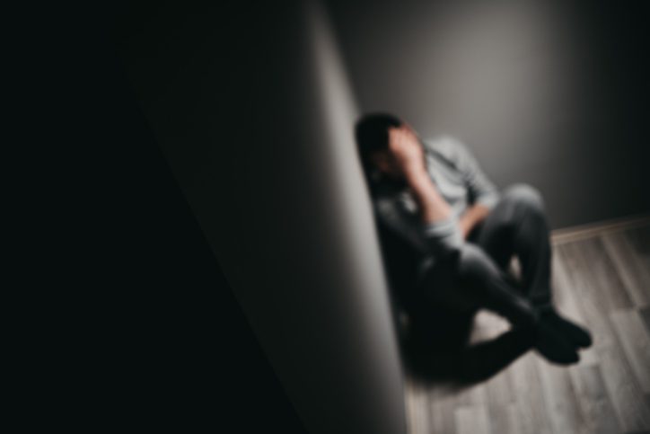 sad person sitting in a corner upset
