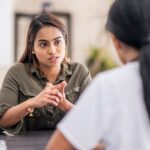 Woman sitting across from a healthcare professional, engaged in a serious conversation—suggesting a counseling or addiction treatment session.
