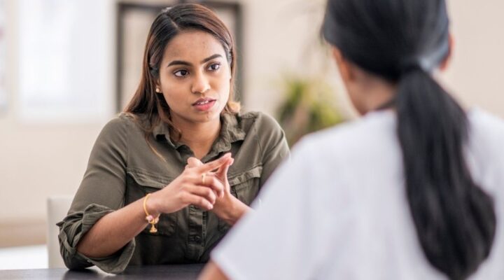 Woman sitting across from a healthcare professional, engaged in a serious conversation—suggesting a counseling or addiction treatment session.
