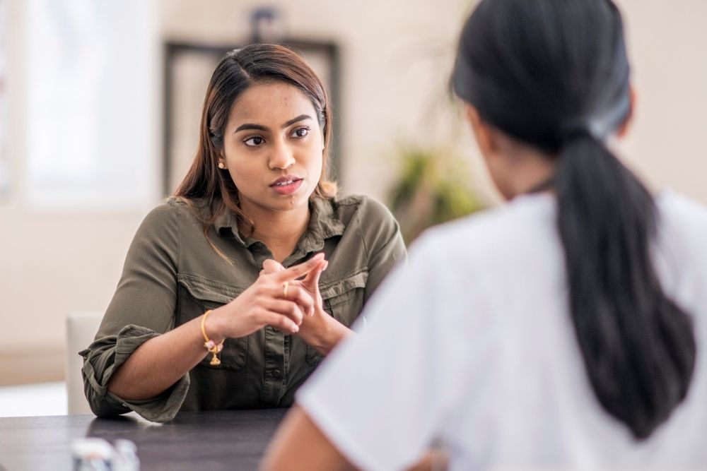 Woman sitting across from a healthcare professional, engaged in a serious conversation—suggesting a counseling or addiction treatment session.